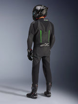 Piloto visto de costas a usar o Fato de Pele Alpinestars GP Force V2, 1 Peça, preto com detalhes em verde, corcova aerodinâmica, combinado com capacete de fibra de carbono preto, botas de corrida e luvas pretas, equipamento de motociclismo de alta performance