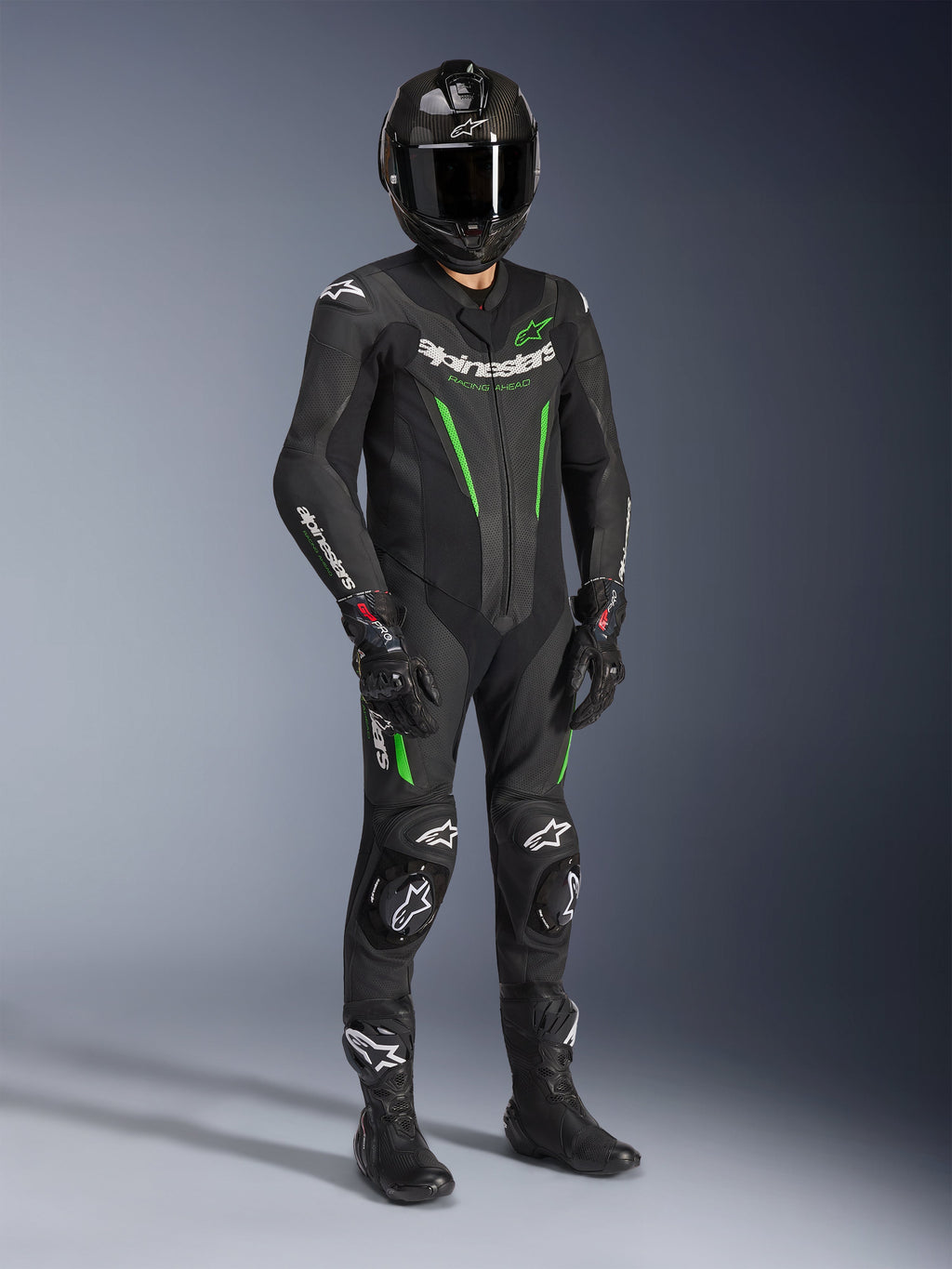 Fato de Pele Alpinestars GP Force V2 - 1 Peça, preto e verde, usado com capacete preto a condizer, luvas de corrida e botas, com pormenores em verde vivo e logótipo Alpinestars em branco, equipamento profissional de pista e condução desportiva