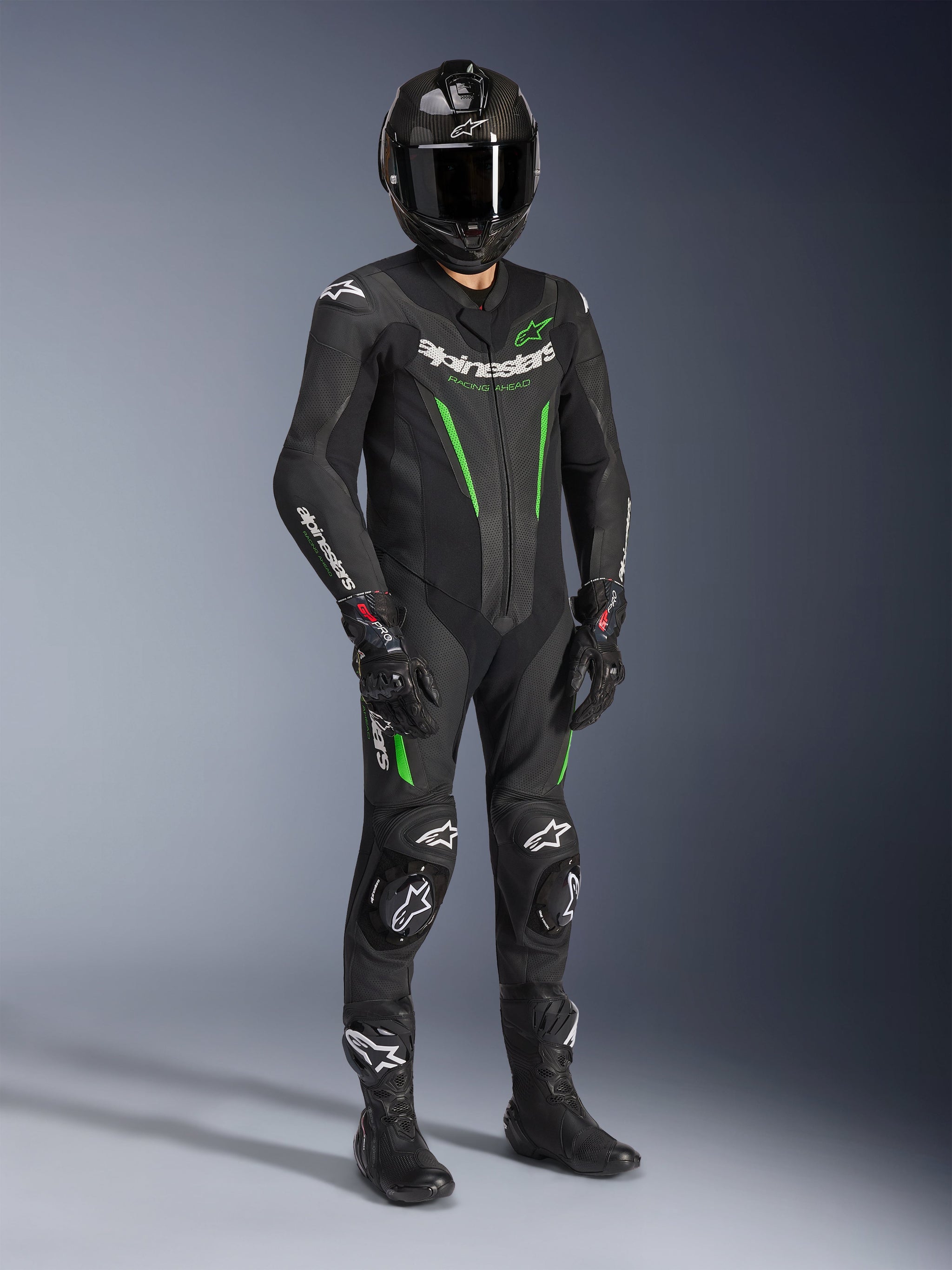 Fato de Pele Alpinestars GP Force V2 - 1 Peça, preto e verde, usado com capacete preto a condizer, luvas de corrida e botas, com pormenores em verde vivo e logótipo Alpinestars em branco, equipamento profissional de pista e condução desportiva