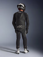 Fato de Cabedal Alpinestars GP Force V2 de 2 Peças em preto, vista traseira completa mostrando a corcova aerodinâmica e logótipo Tech-Air Ready, combinado com capacete preto e branco e botas de corrida brancas para performance profissional em pista