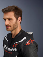 Fato de Pele Alpinestars GP Force V2 de 2 Peças, grande plano do casaco vestido por modelo masculino, preto, branco e vermelho fluo, com pele perfurada, logótipo de estrela vermelha no ombro, corcunda aerodinâmica e branding Alpinestars no peito, equipamento profissional de motociclismo de competição