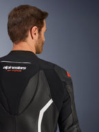 Fato de Pele GP Force V2 de 2 Peças, grande plano da parte superior das costas e do ombro num modelo masculino, em pele preta com pormenores em branco e vermelho, marca Alpinestars GP Force, realçando painéis perfurados e zonas elásticas em acordeão para competição.