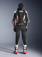 Rear view of the Alpinestars Stella GP-R7 2-Piece Leather Suit, Black White and Red Fluo, featuring an aerodynamic hump with GP-R7 branding and Tech-Air Ready logo, worn with matching racing boots and gloves, professional motorcycle gear for women