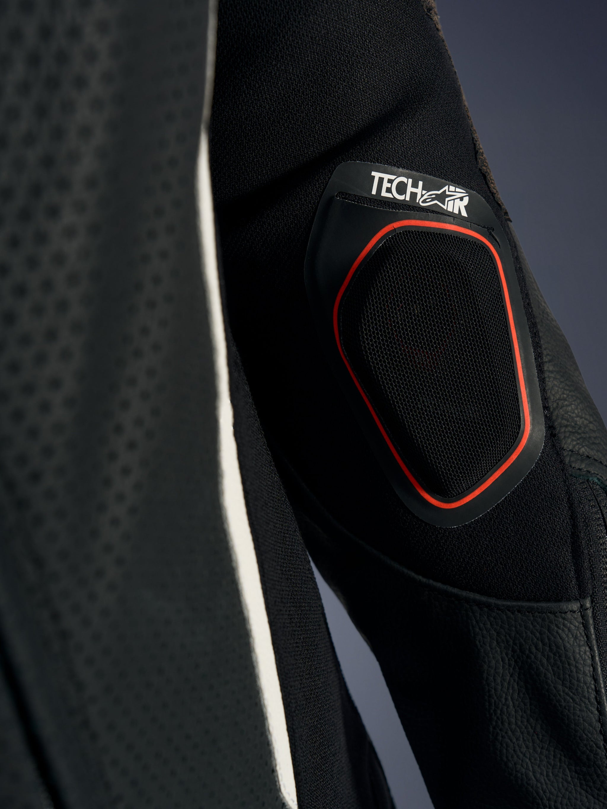 Fato de cabedal Alpinestars Stella GP-R7 de 1 peça, preto, vista detalhada do indicador de compatibilidade do airbag Tech-Air na manga, com painel de malha de contorno vermelho e construção em cabedal perfurado