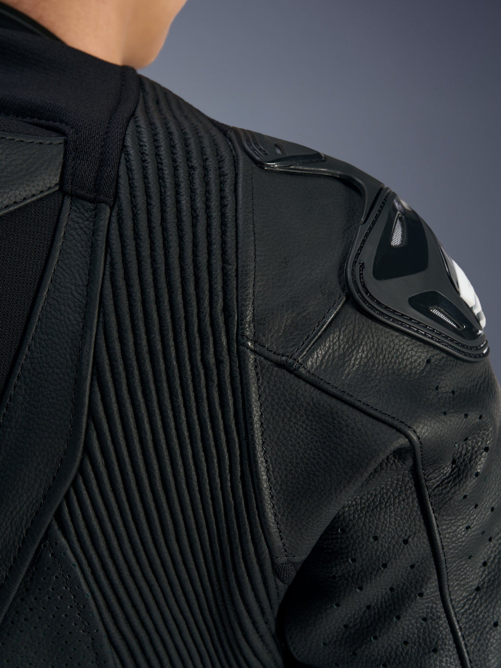 Fato de Cabedal Stella GP-R7 Feminino da Alpinestars, preto, detalhe do ombro com slider de ombro DFS RR, painéis de cabedal em acordeão para mobilidade e cabedal perfurado para ventilação.