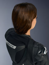 Grande plano da parte superior das costas e ombro do Fato de Cabedal de 1 Peça Alpinestars Stella GP-R7 em preto, com a corcova aerodinâmica com a marca 'GP-R7', o protetor de ombro DFS RR com o logótipo Alpinestars e sanfonas de couro elástico multidirecionais.