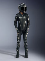 Piloto feminina a usar o fato de cabedal de uma peça Alpinestars Stella GP-R7 em preto, equipamento completo de corrida de motociclismo incluindo capacete Supertech R10, luvas pretas e brancas e botas de corrida, com pormenores em branco, painéis de cabedal perfurado e bossa aerodinâmica para desempenho profissional em pista.
