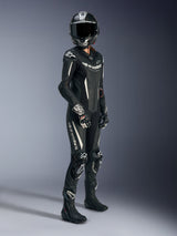 Piloto feminina a usar o Fato de Cabedal de 1 Peça Alpinestars Stella GP-R7 em preto e branco, com cabedal perfurado e detalhes do logótipo em branco, combinado com um capacete de corrida em fibra de carbono, luvas de corrida pretas e brancas e botas pretas para um conjunto completo pronto para a pista.