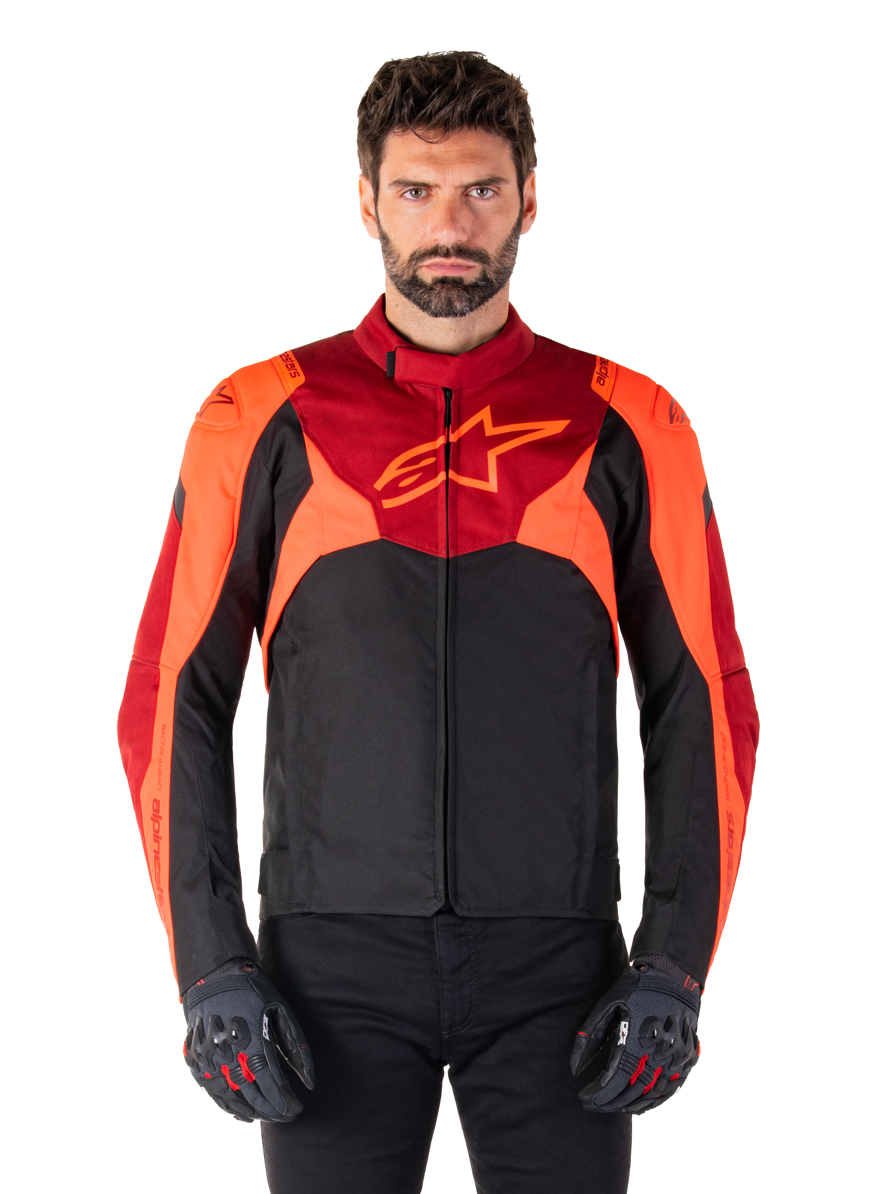 Alpinestars T-Jaws V4 Waterproof Jacket, casaco de motociclismo têxtil desportivo, preto com pormenores em vermelho fluo e vermelho escuro, usado por um modelo masculino com luvas a condizer, equipamento técnico de condução com logótipo de estrela proeminente no peito.