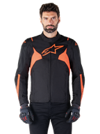 Casaco Impermeável Alpinestars T-Jaws V4, casaco desportivo de motociclismo, preto e vermelho fluorescente, com detalhes em néon e um logótipo de estrela proeminente no peito, usado por um modelo masculino com luvas de motociclismo pretas, design têxtil elegante de inspiração racing