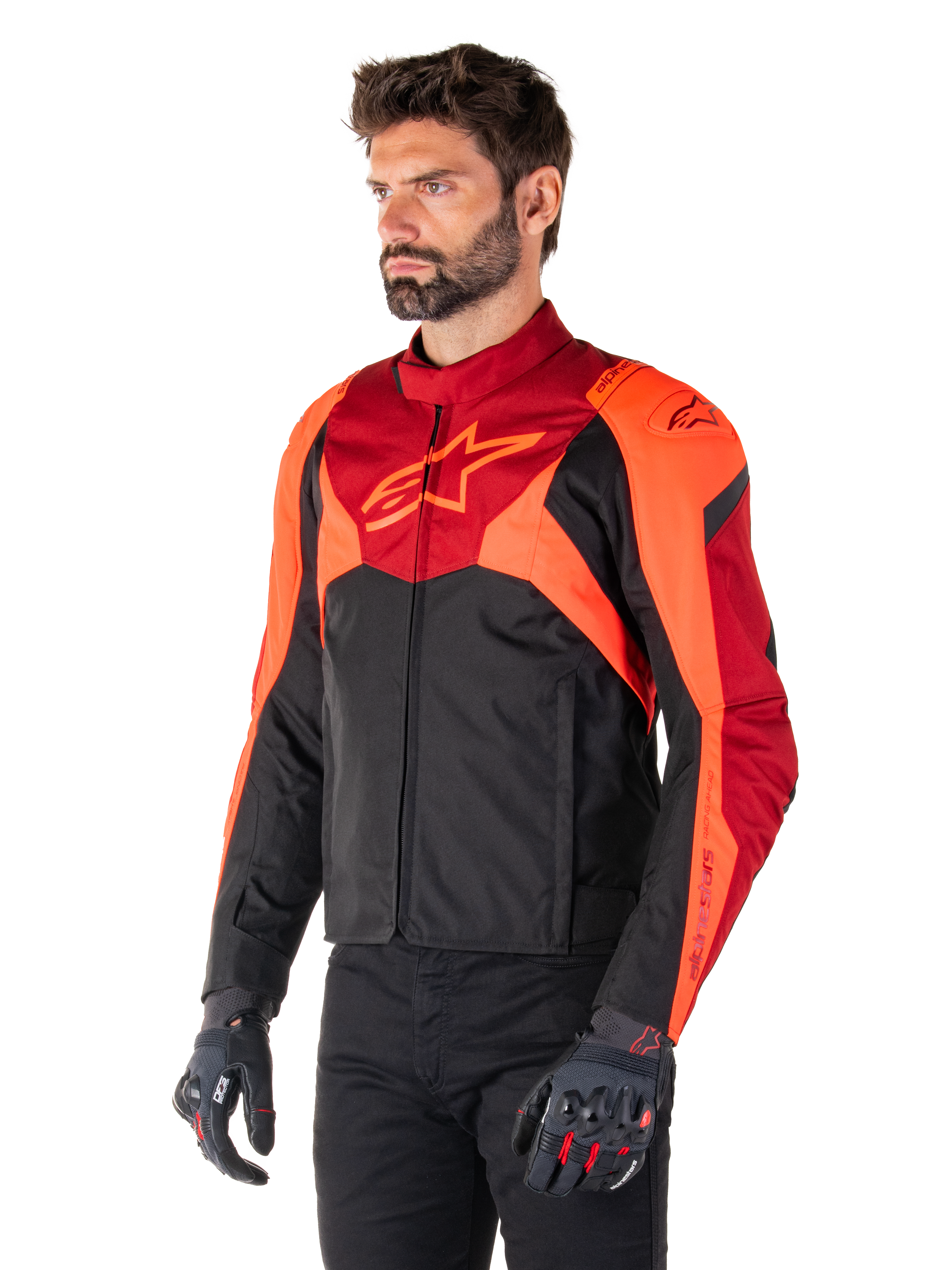 Casaco Impermeável Alpinestars T-Jaws V4, Preto, Vermelho Fluo e Vermelho Escuro, vestido por um modelo masculino com calças pretas e luvas de motociclismo, silhueta desportiva agressiva com o logótipo Alpinestars no peito, vista de três quartos