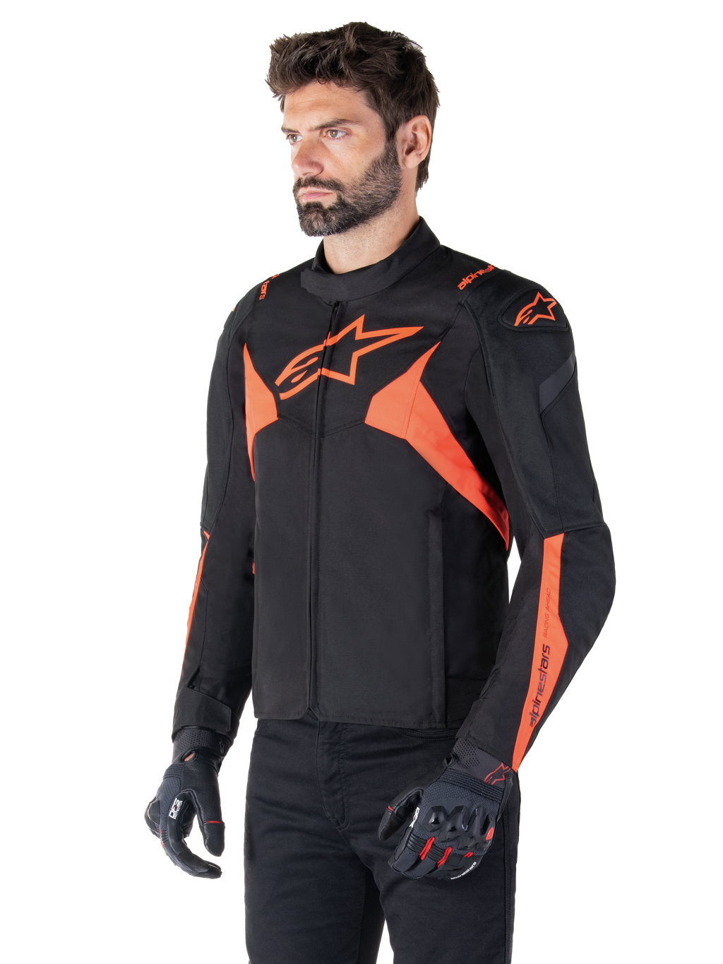 Alpinestars T-Jaws V4 Waterproof Jacket, preto e vermelho fluo, casaco desportivo de motociclismo vestido por um modelo masculino, com logótipos de estrela cor de laranja destacados no peito e nos ombros, combinado com luvas e calças pretas