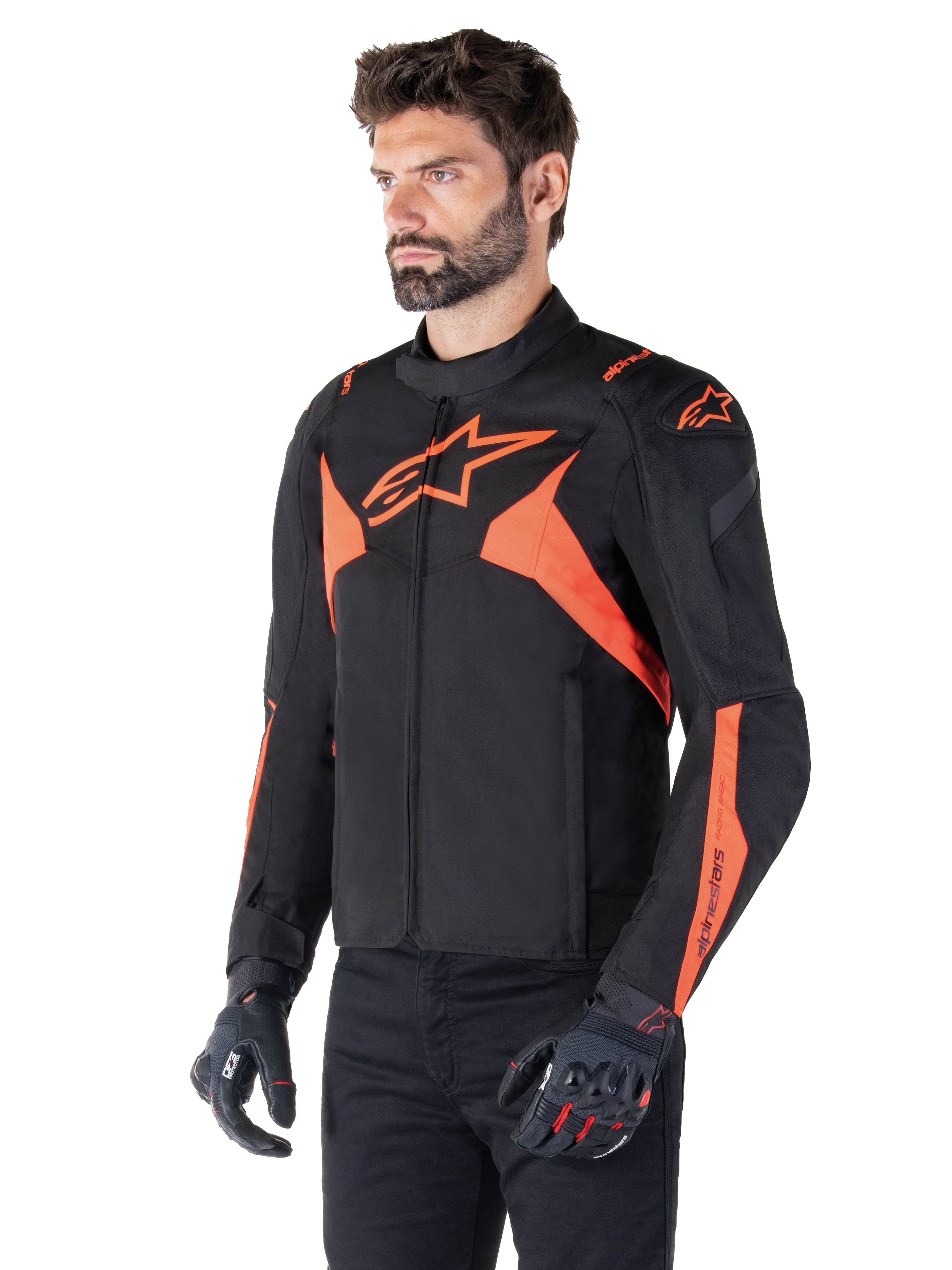 Alpinestars T-Jaws V4 Waterproof Jacket, preto e vermelho fluo, casaco desportivo de motociclismo vestido por um modelo masculino, com logótipos de estrela cor de laranja destacados no peito e nos ombros, combinado com luvas e calças pretas