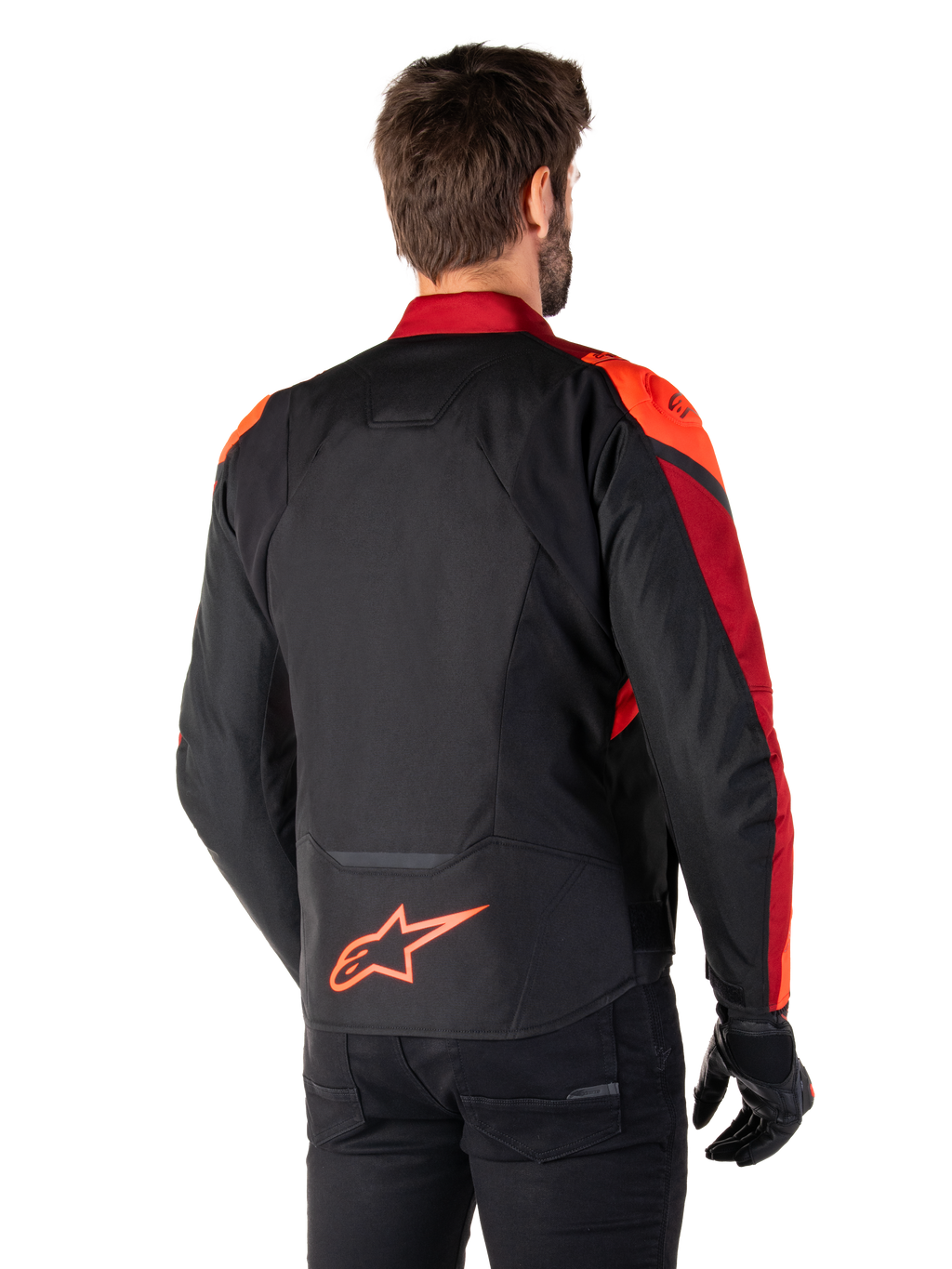 Vista traseira de um homem a usar o Casaco Impermeável Alpinestars T-Jaws V4 em preto, vermelho fluo e vermelho escuro, com pormenores em vermelho vibrante nos ombros e mangas, um logótipo Alpinestars em vermelho fluo na parte inferior das costas, combinado com calças e luvas pretas.