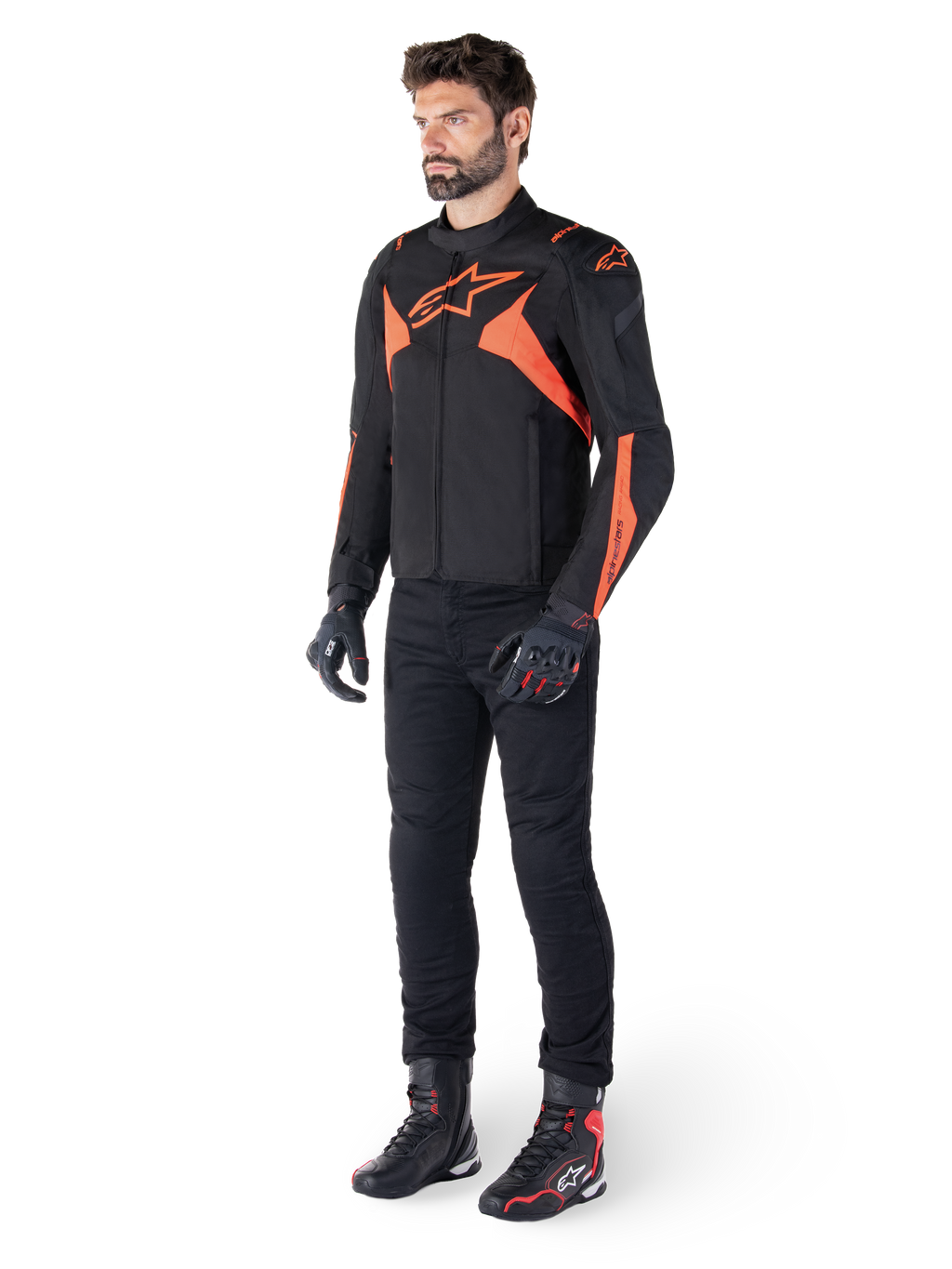 Casaco Alpinestars T-Jaws V4 Waterproof, preto e vermelho fluo, usado por um modelo masculino com calças, luvas e botas pretas, apresentando detalhes em laranja vibrante e o logótipo Alpinestars, design desportivo para motociclismo