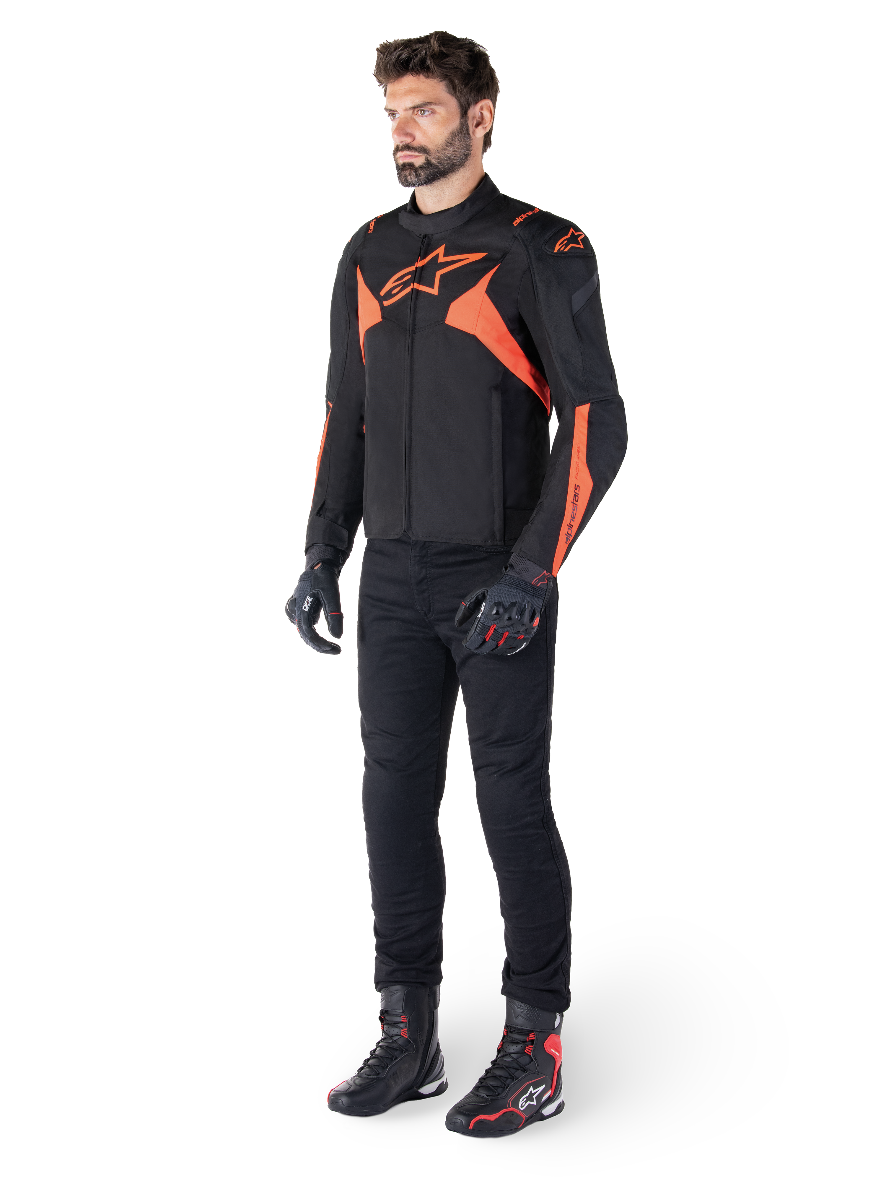 Casaco Alpinestars T-Jaws V4 Waterproof, preto e vermelho fluo, usado por um modelo masculino com calças, luvas e botas pretas, apresentando detalhes em laranja vibrante e o logótipo Alpinestars, design desportivo para motociclismo