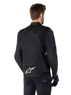 Alpinestars T-Jaws V4 Waterproof Jacket, Black and White, rear view, textile sport motorcycle jacket with white logo on the lower back, worn with black gloves and pants, featuring a revised sport fit silhouette
