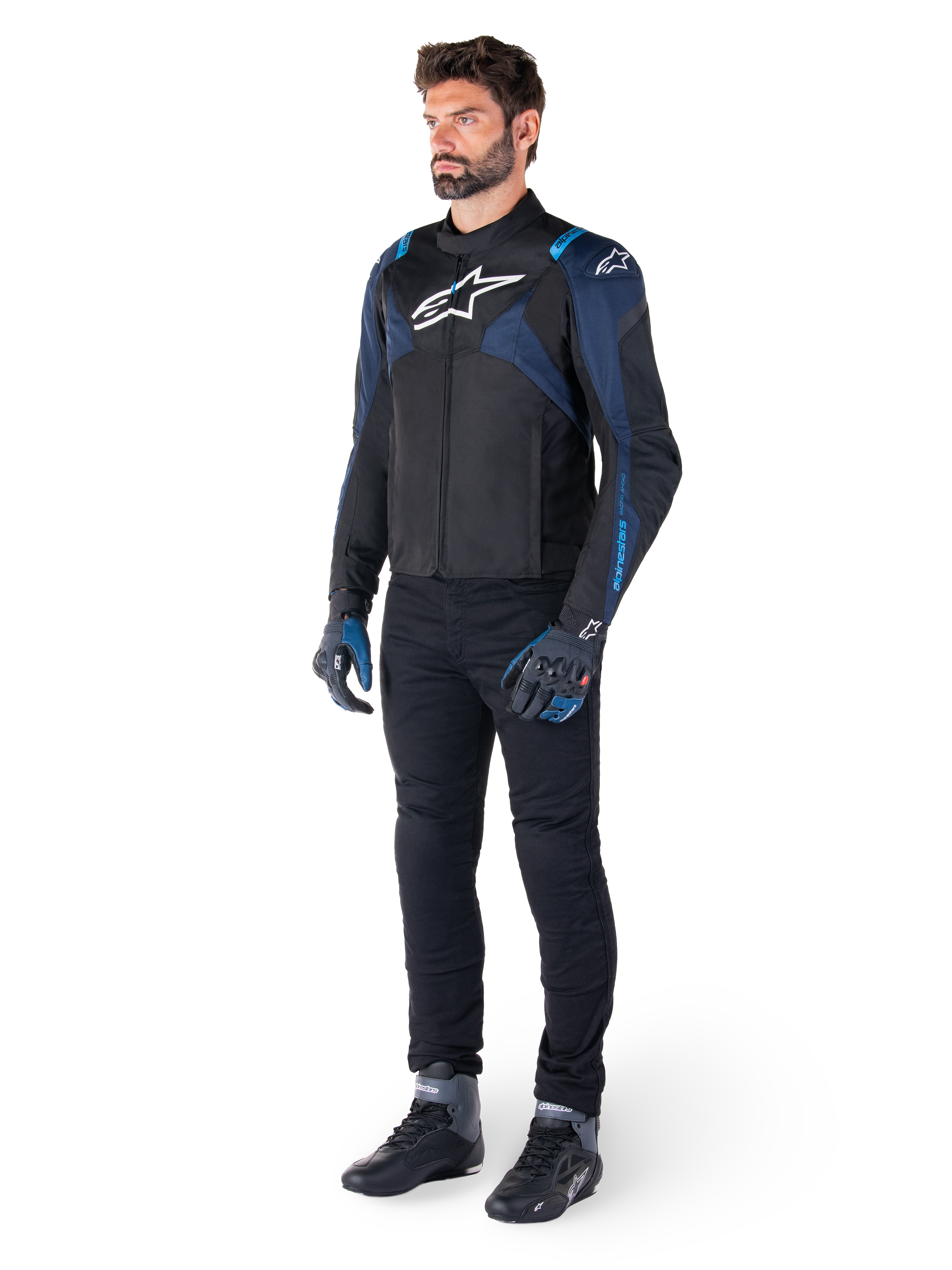 Casaco Impermeável Alpinestars T-Jaws V4 em preto, azul escuro e azul Blithe, vestido por um modelo com calças de motociclismo pretas e botas de condução, com logótipo Alpinestars branco no peito e detalhes azuis nos ombros, equipamento de condução com ajuste desportivo