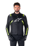 Casaco Impermeável Alpinestars T-SPS V2, casaco de motociclismo, preto com detalhes em branco e amarelo fluorescente, usado por um modelo com luvas pretas, com um logótipo de estrela branco no peito e riscas amarelo néon nas mangas e ombros, equipamento têxtil de estilo desportivo para todas as condições meteorológicas
