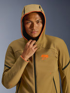Alpinestars Aeroshell Waterproof Jacket, Dark Khaki Black Orange Fluo, model wearing the jacket with the hood up, featuring vibrant orange fluo trim and an orange ASTARS logo, sleek black accents, modern sport-styled waterproof softshell