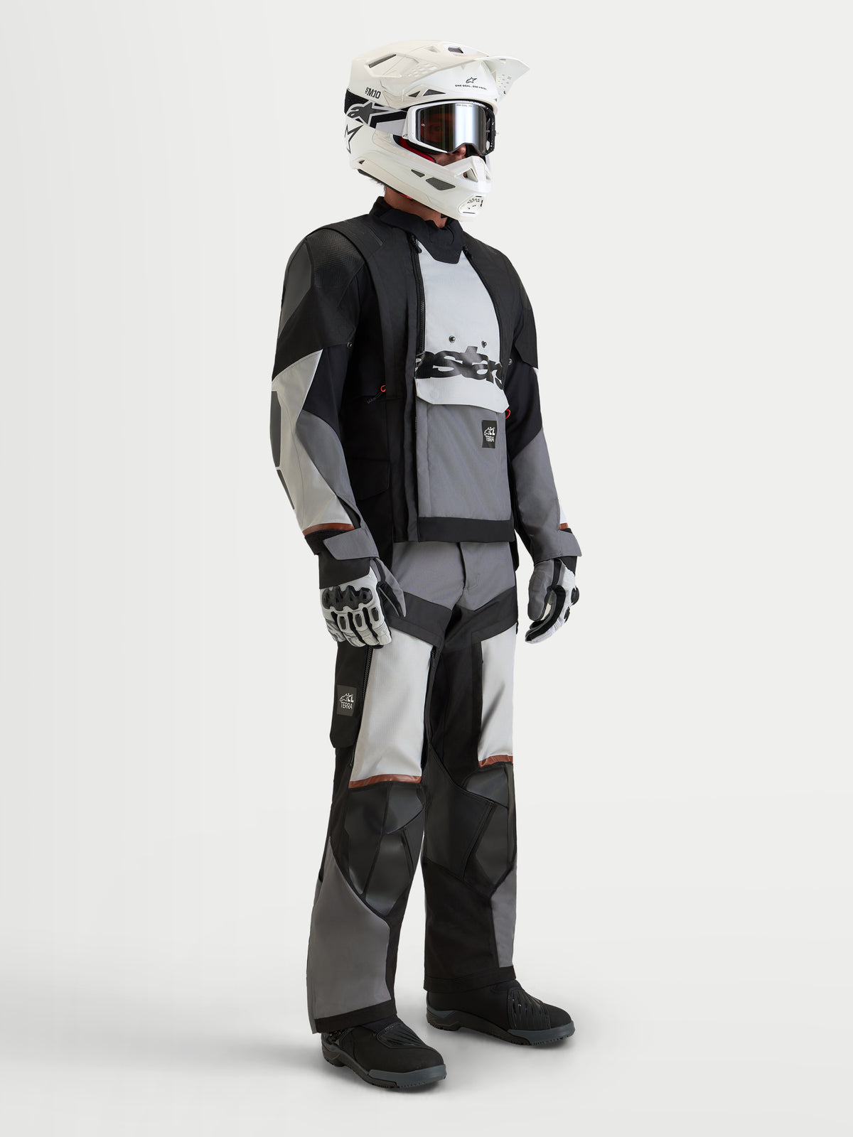 Alpinestars Harok V2 Drystar, casaco de moto para homem de aventura, cinzento escuro, cinzento gelo e preto, modelo a vestir equipamento de proteção completo com capacete e luvas, construção impermeável e ventilação modular todo-o-terreno