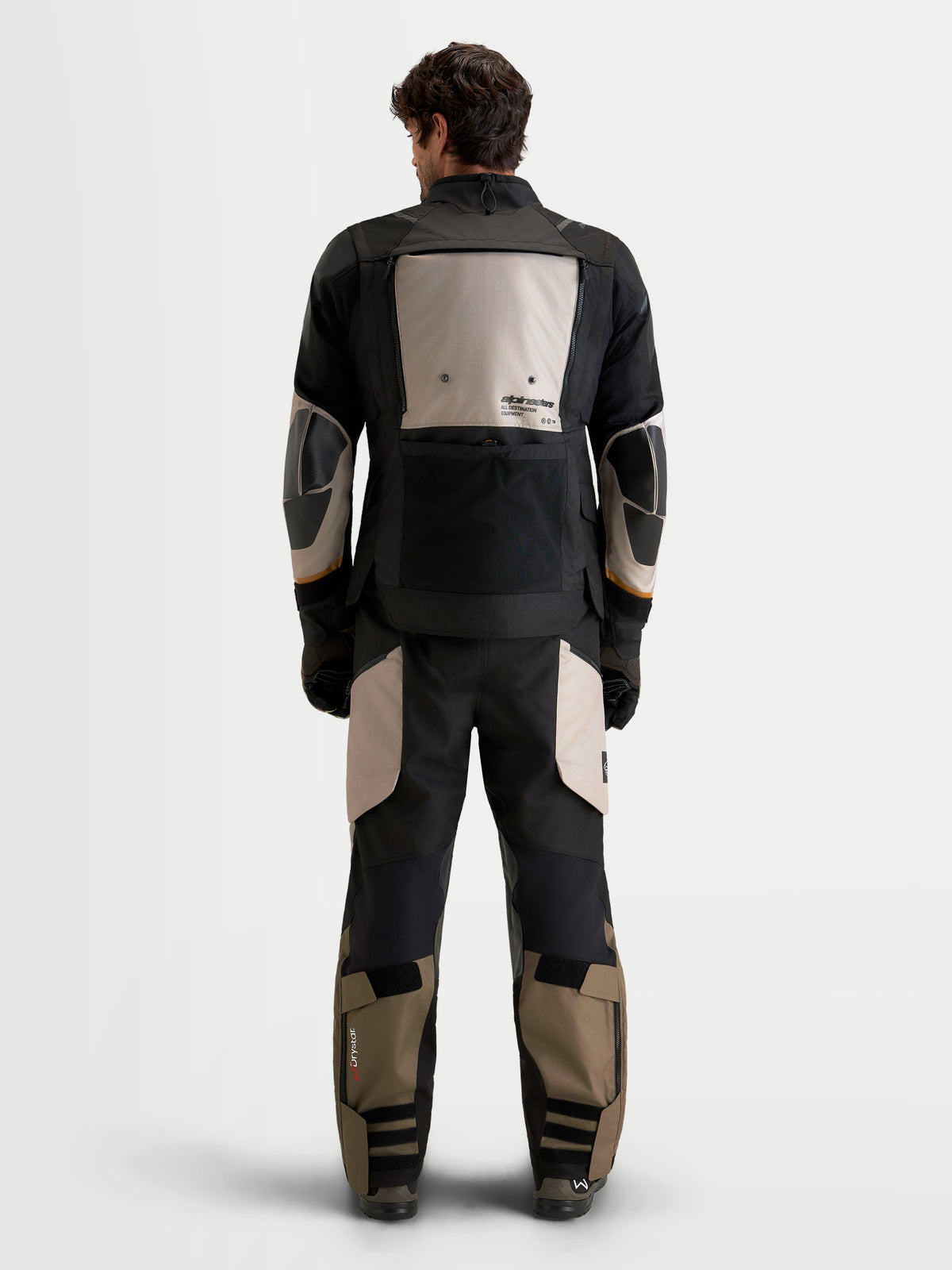 Alpinestars Harok V2 Drystar gear set, casaco e calças de moto adventure para homem em preto e caqui, vista traseira num modelo a vestir equipamento têxtil impermeável com pormenores de proteção reforçada