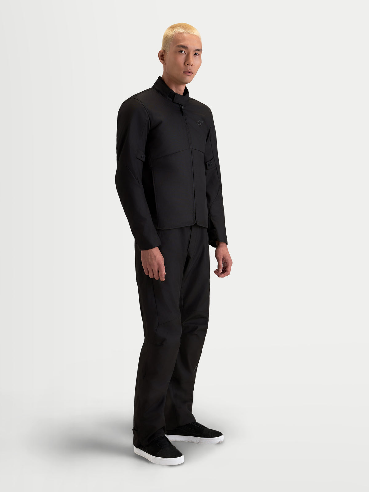 Alpinestars C-1 Waterproof casaco de moto urbano contemporâneo para homem, preto, vista lateral num modelo a vestir calças a condizer, com construção em poliéster impermeável e gola de acabamento suave