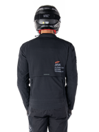 Casaco Alpinestars AMT-8 Stretch Drystar® XF, vista traseira, preto, usado com capacete e calças pretas, com logótipo Alpinestars Motion Technology nas costas, design de touring de aventura com material elástico ergonómico.