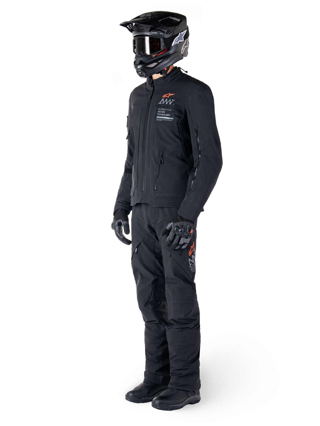 Casaco Alpinestars AMT-8 Stretch Drystar® XF, casaco de motociclismo de aventura, preto, usado com calças, capacete e luvas a condizer, com o logótipo Alpinestars Motion Technology e detalhes em laranja, construção elástica durável para condução de aventura