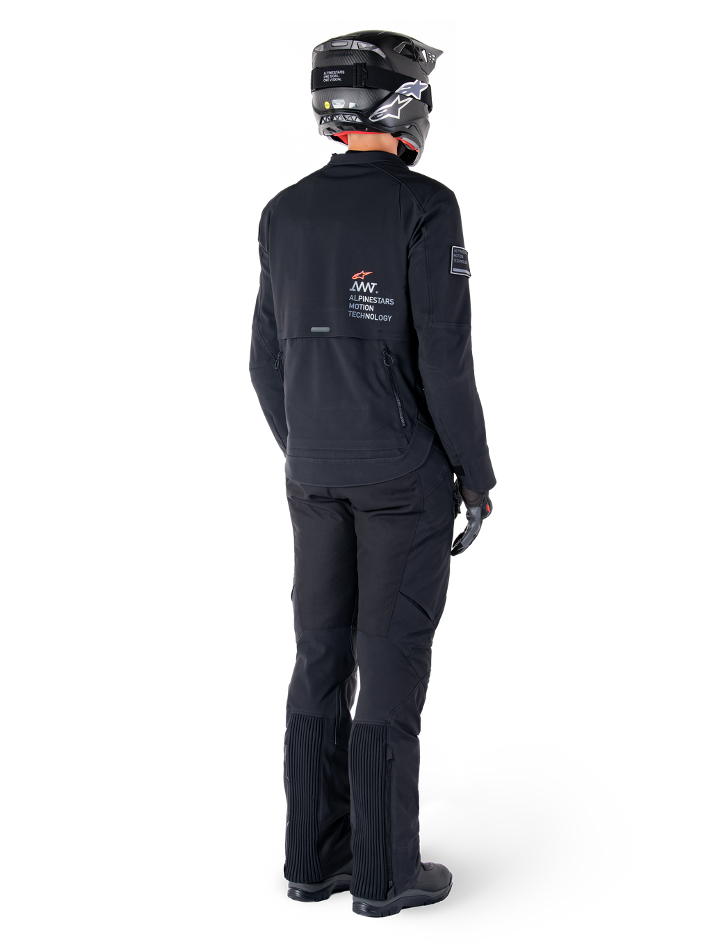 Casaco Alpinestars AMT-8 Stretch Drystar® XF, preto, vista traseira de um motociclista a usar o casaco com calças pretas a condizer e um capacete preto, com a marca 'Alpinestars Motion Technology' nas costas, material elástico técnico para motociclismo de aventura