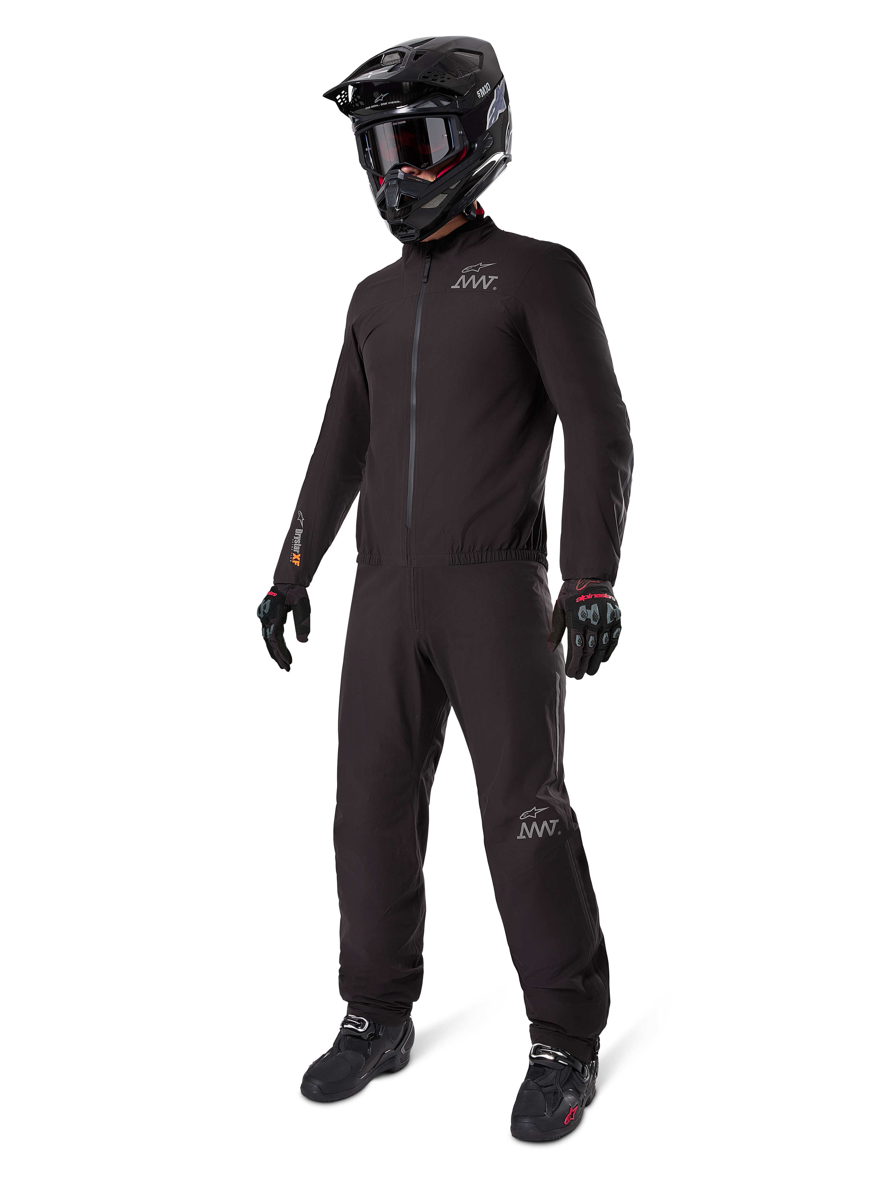 Alpinestars AMT-8 Stretch Drystar® XF Liner, fato de motociclismo impermeável preto, usado com capacete preto, óculos e luvas, com logótipos AMT e Drystar XF, equipamento de aventura funcional para proteção em todas as condições climatéricas.