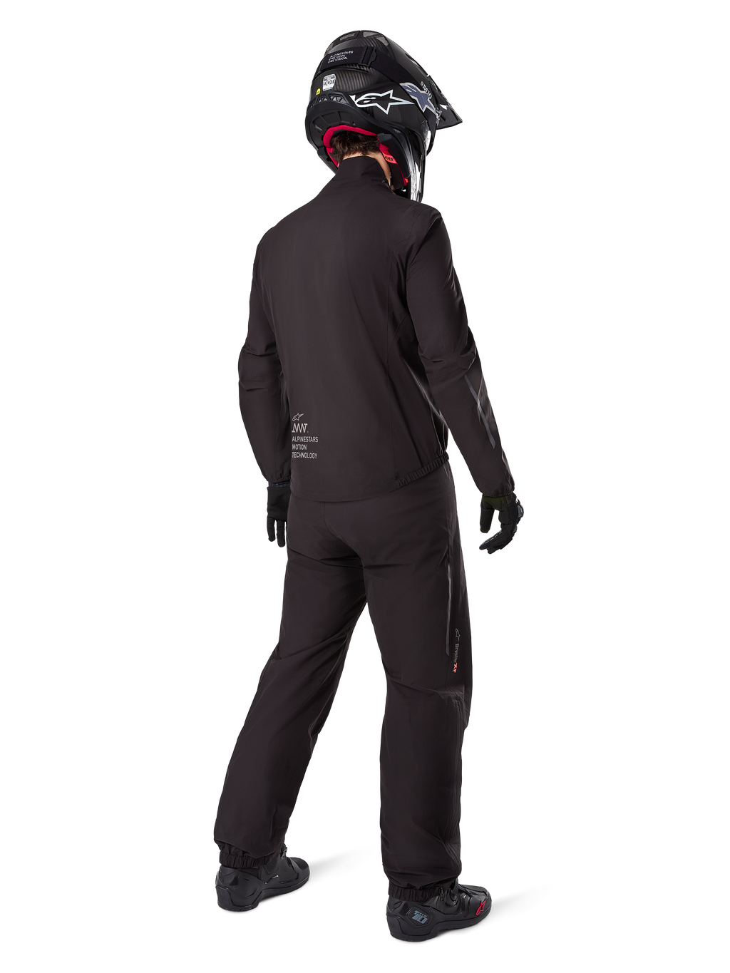 Vista traseira de um motociclista com o forro do casaco Alpinestars AMT-8 Stretch Drystar® XF, equipamento técnico de motociclismo preto, calças a condizer e capacete preto, marca "AMT Alpinestars Motion Technology" nas costas, design minimalista para adventure touring
