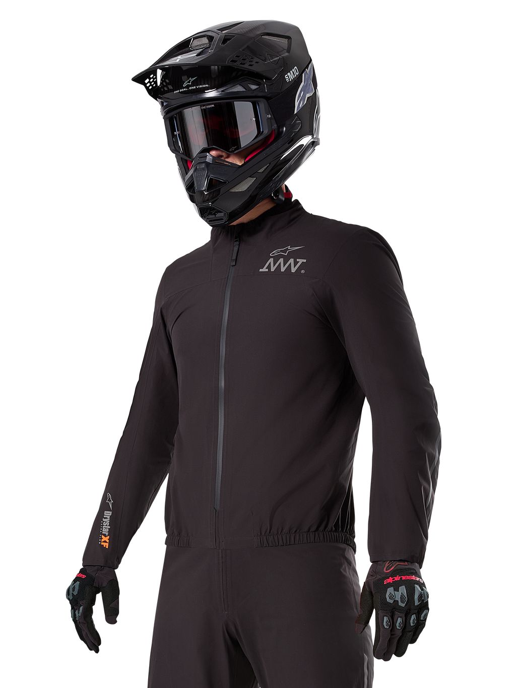 Piloto a usar o forro Alpinestars AMT-8 Stretch Drystar® XF, casaco elástico preto à prova de vento e impermeável, com o logótipo AMT no peito e a marca Drystar XF na manga, combinado com um capacete de aventura preto e luvas de proteção.