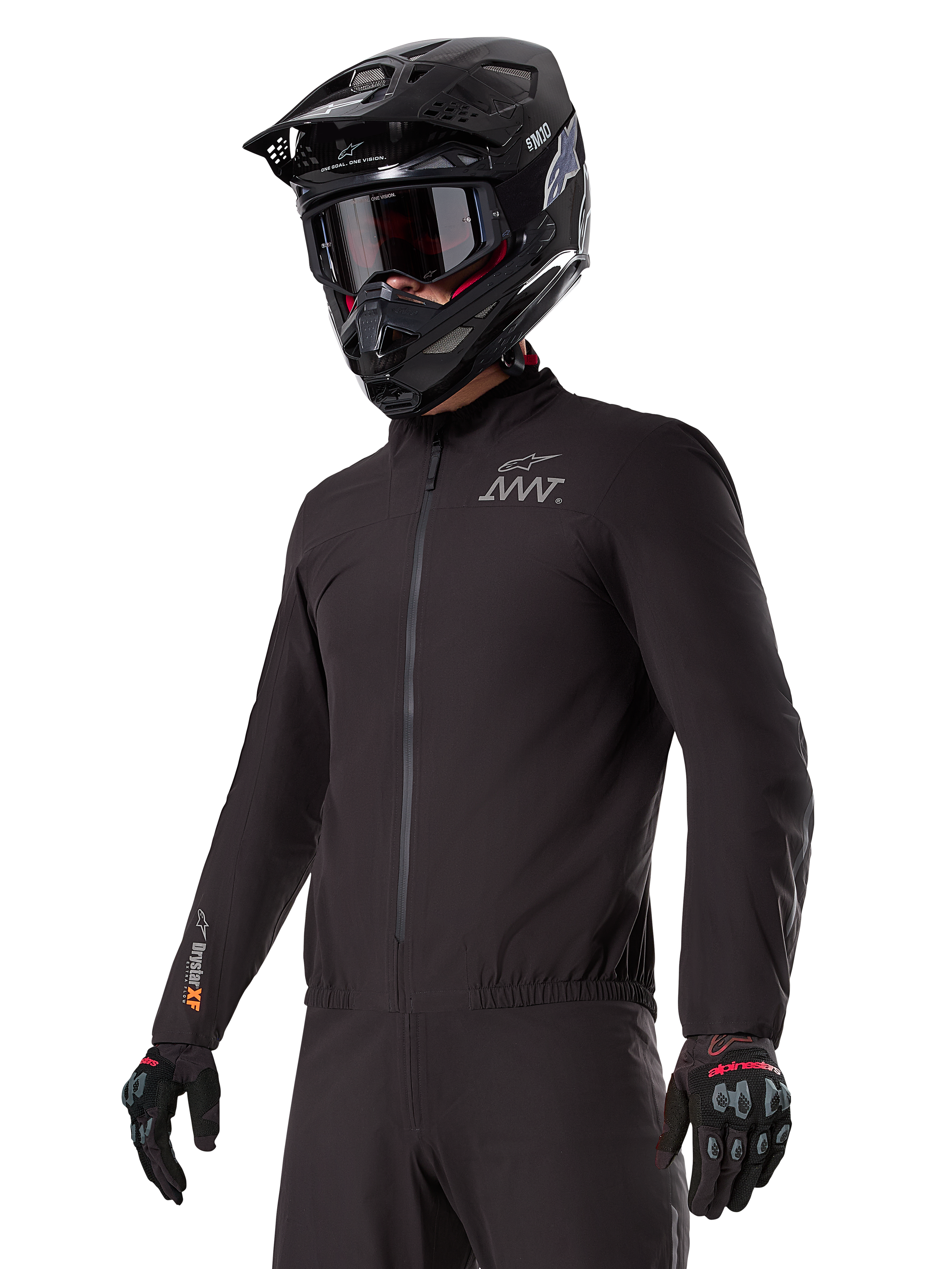 Piloto a usar o forro Alpinestars AMT-8 Stretch Drystar® XF, casaco elástico preto à prova de vento e impermeável, com o logótipo AMT no peito e a marca Drystar XF na manga, combinado com um capacete de aventura preto e luvas de proteção.