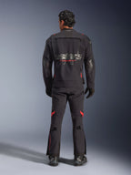 Vista traseira de um motociclista com o Casaco Alpinestars Halo Pro Drystar® XF Laminated em Black Dark Shadow, com um grande logótipo astars cinzento e marca Alpinestars a vermelho, painéis de ventilação modulares nas costas, calças de aventura a condizer e botas pretas.
