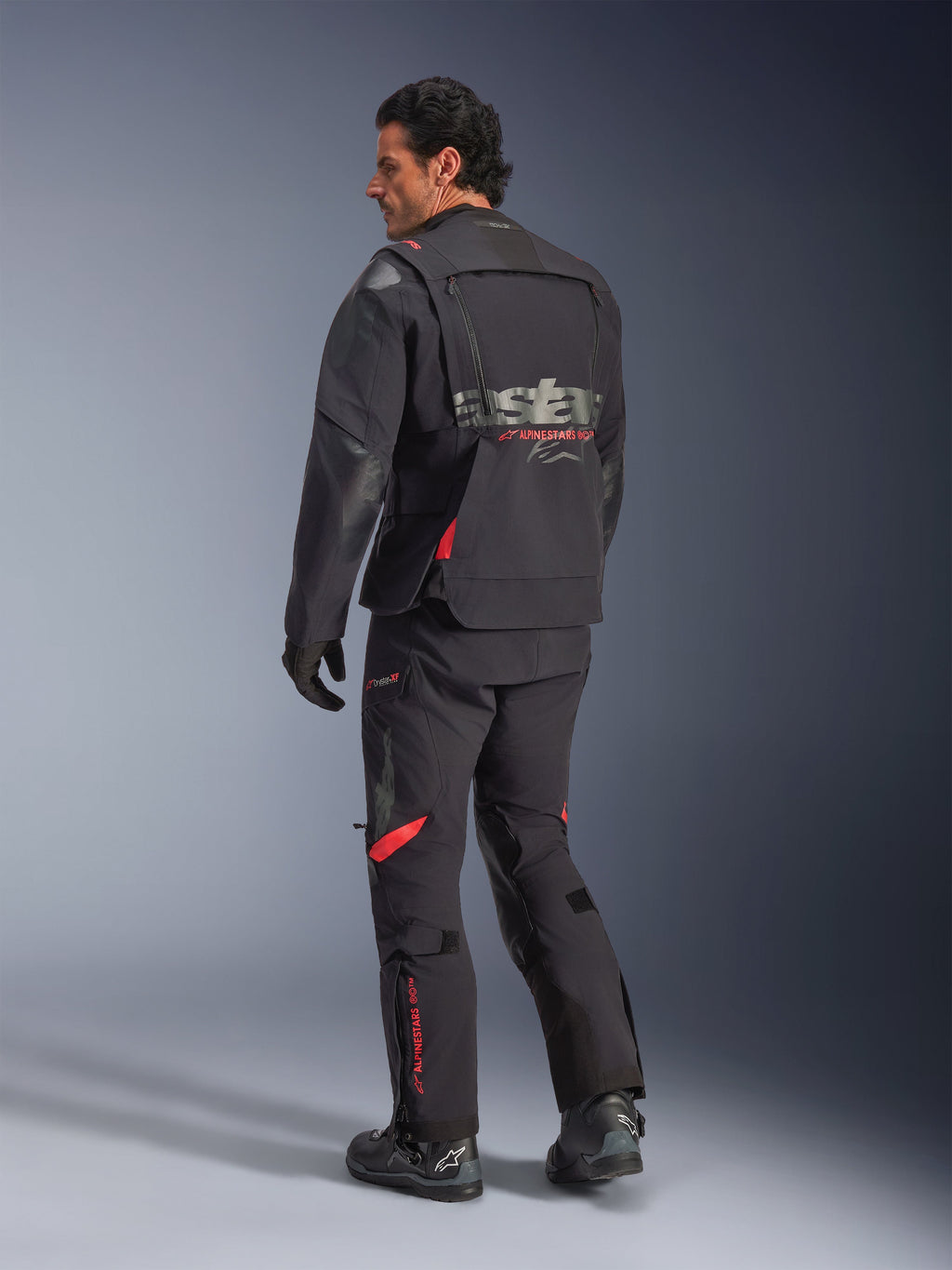 Casaco Alpinestars Halo Pro Drystar® XF Laminado, casaco de motociclismo de aventura, preto Dark Shadow com detalhes em vermelho, vista traseira, usado com calças e botas a condizer, com logótipo cinzento nas costas, design têxtil modular para adventure touring