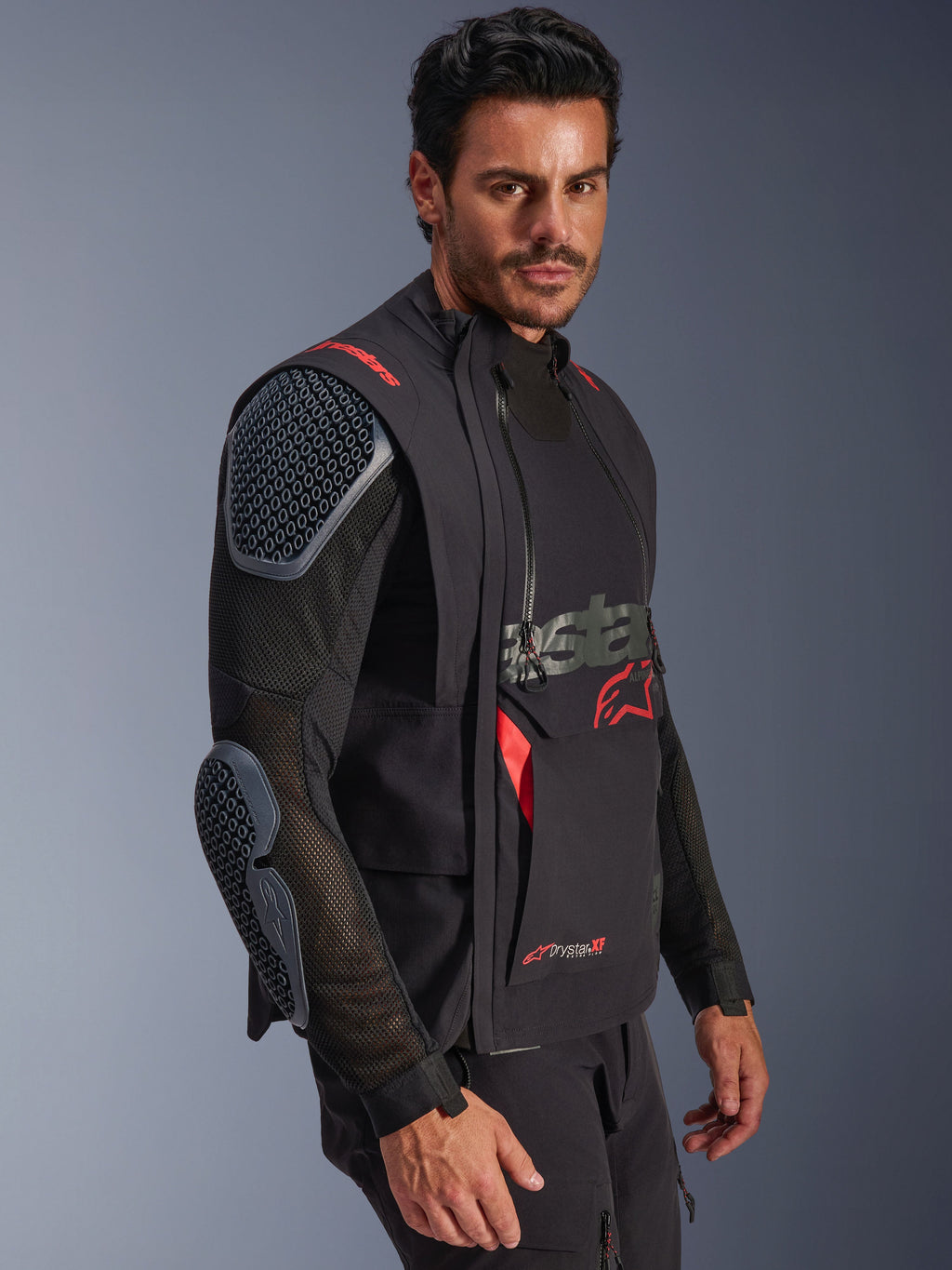 Alpinestars Halo Pro Drystar® XF Laminated Jacket, Preto e Dark Shadow, casaco de motociclismo de aventura usado por modelo, configuração modular com mangas de malha e proteções integradas nos ombros e cotovelos, detalhes do logótipo em vermelho e fechos técnicos impermeáveis.