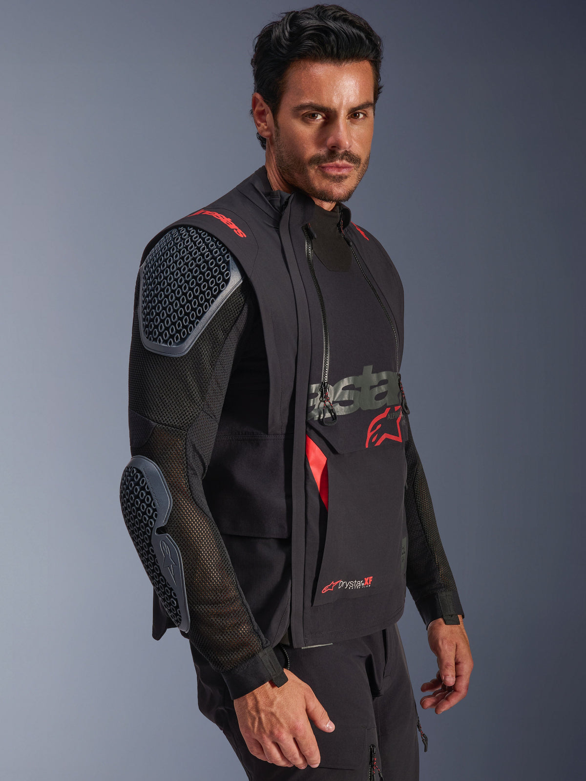 Alpinestars Halo Pro Drystar® XF Laminated Jacket, Preto e Dark Shadow, casaco de motociclismo de aventura usado por modelo, configuração modular com mangas de malha e proteções integradas nos ombros e cotovelos, detalhes do logótipo em vermelho e fechos técnicos impermeáveis.