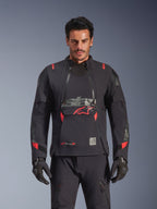 Alpinestars Halo Pro Drystar® XF Laminated Jacket, casaco de motociclismo de aventura, preto Dark Shadow com detalhes em vermelho, modelo masculino a usar equipamento técnico completo incluindo luvas e calças a condizer, vista frontal destacando os painéis de ventilação modulares no peito e a construção impermeável