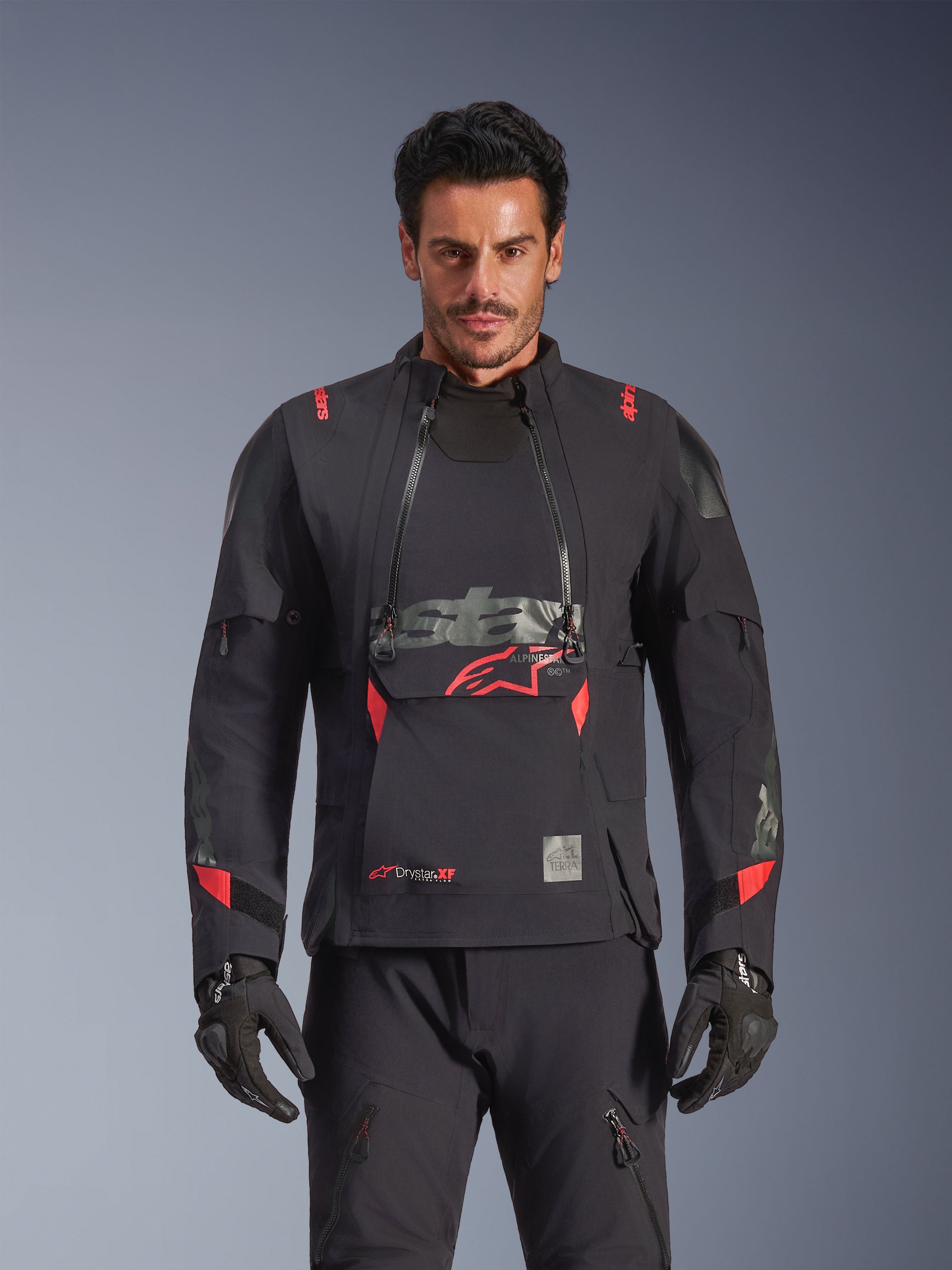 Alpinestars Halo Pro Drystar® XF Laminated Jacket, casaco de motociclismo de aventura, preto Dark Shadow com detalhes em vermelho, modelo masculino a usar equipamento técnico completo incluindo luvas e calças a condizer, vista frontal destacando os painéis de ventilação modulares no peito e a construção impermeável