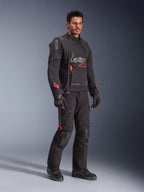 Motociclista com o Casaco Laminado Alpinestars Halo Pro Drystar® XF em Preto Dark Shadow, equipamento de aventura completo com calças, luvas e botas a condizer, apresentando painéis frontais assimétricos modulares e detalhes da marca em vermelho.
