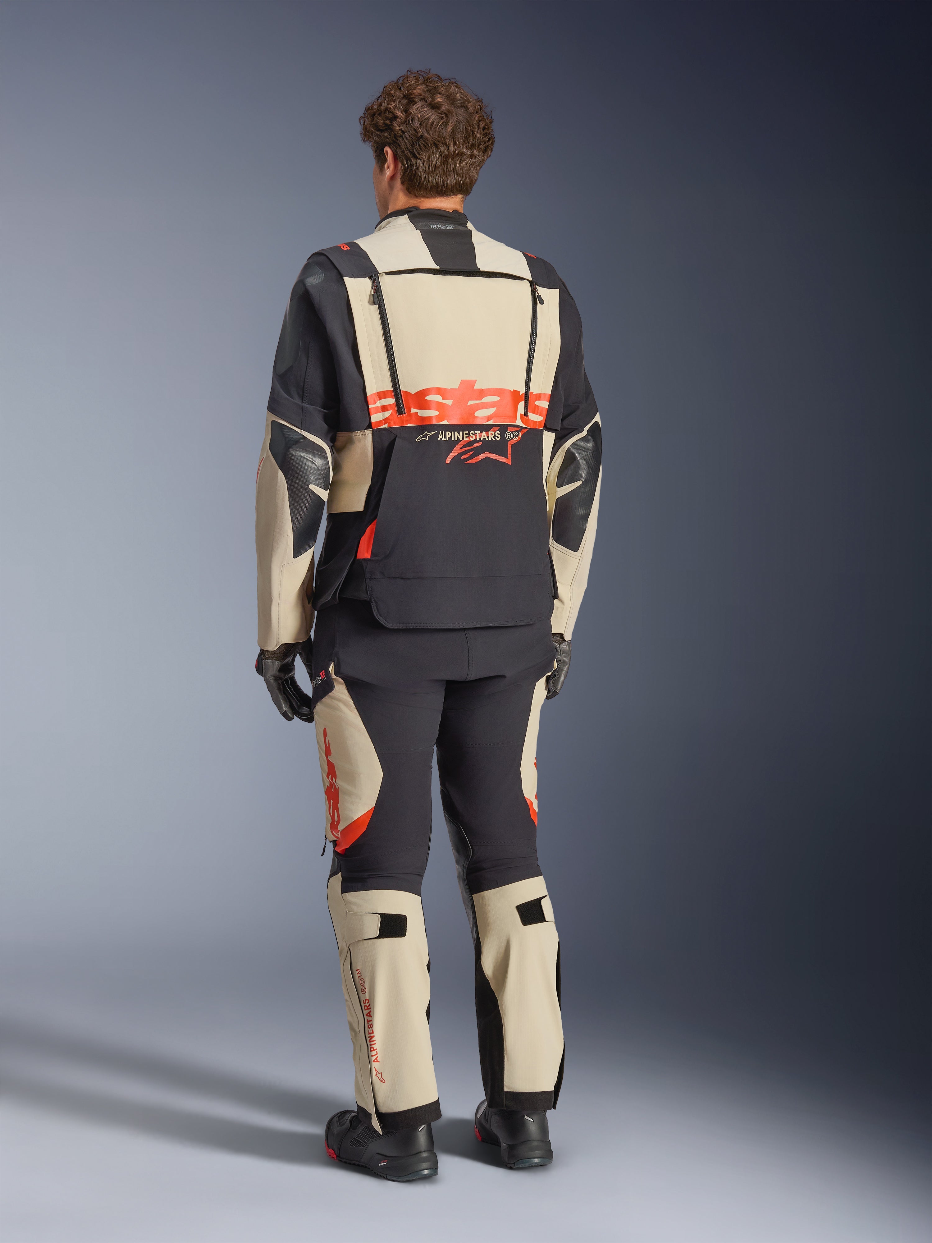 Casaco Alpinestars Halo Pro Drystar® XF Laminado, Mastic Black, vista traseira, casaco de aventura para motociclismo com logótipo 'astars' grande a laranja na parte de trás, usado com calças técnicas e botas a condizer, design modular para terrenos versáteis