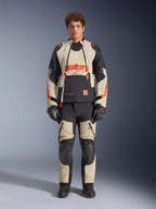 Casaco Alpinestars Halo Pro Drystar® XF Laminated, Mastic Black, casaco de aventura para motociclismo usado por um modelo com calças e luvas a condizer, painéis têxteis bege e pretos com logótipos vermelhos em destaque, design modular para condução em todo-o-terreno