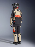 Casaco Alpinestars Halo Pro Drystar® XF Laminado, Mastic Black, vista traseira de um motociclista a usar o fato de aventura completo com calças a condizer, capacete de aventura preto e botas, com um logótipo Alpinestars vermelho em destaque nas costas.