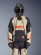 Alpinestars Halo Pro Drystar XF Laminated Jacket, casaco de aventura para motociclismo em Mastic Black e bege com detalhes vermelhos, usado com equipamento de proteção completo incluindo capacete e luvas, com painéis de ventilação modulares e construção laminada 3L.
