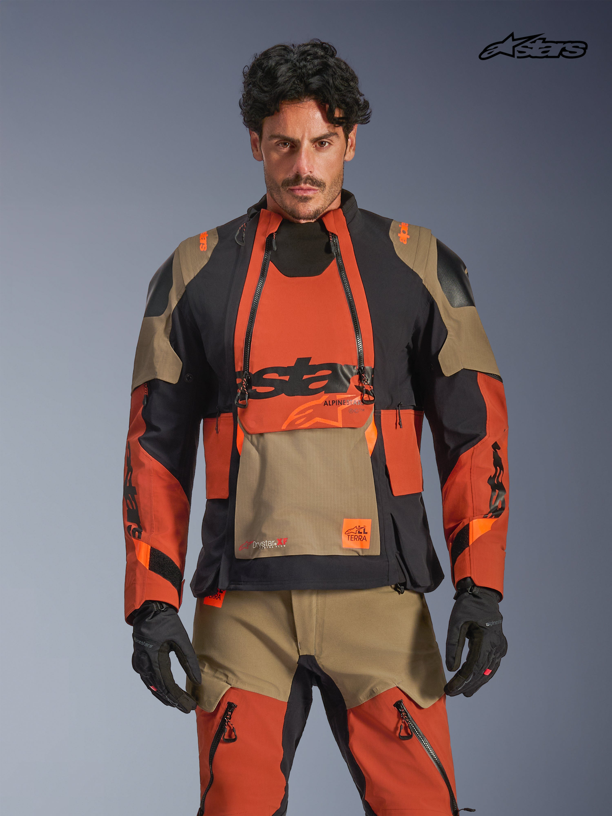 Alpinestars Harok Pro Drystar® XF casaco de moto para homem, castanho, ferrugem e preto, vista frontal num modelo a vestir equipamento a condizer, com construção em tecido impermeável e painéis de ventilação modulares
