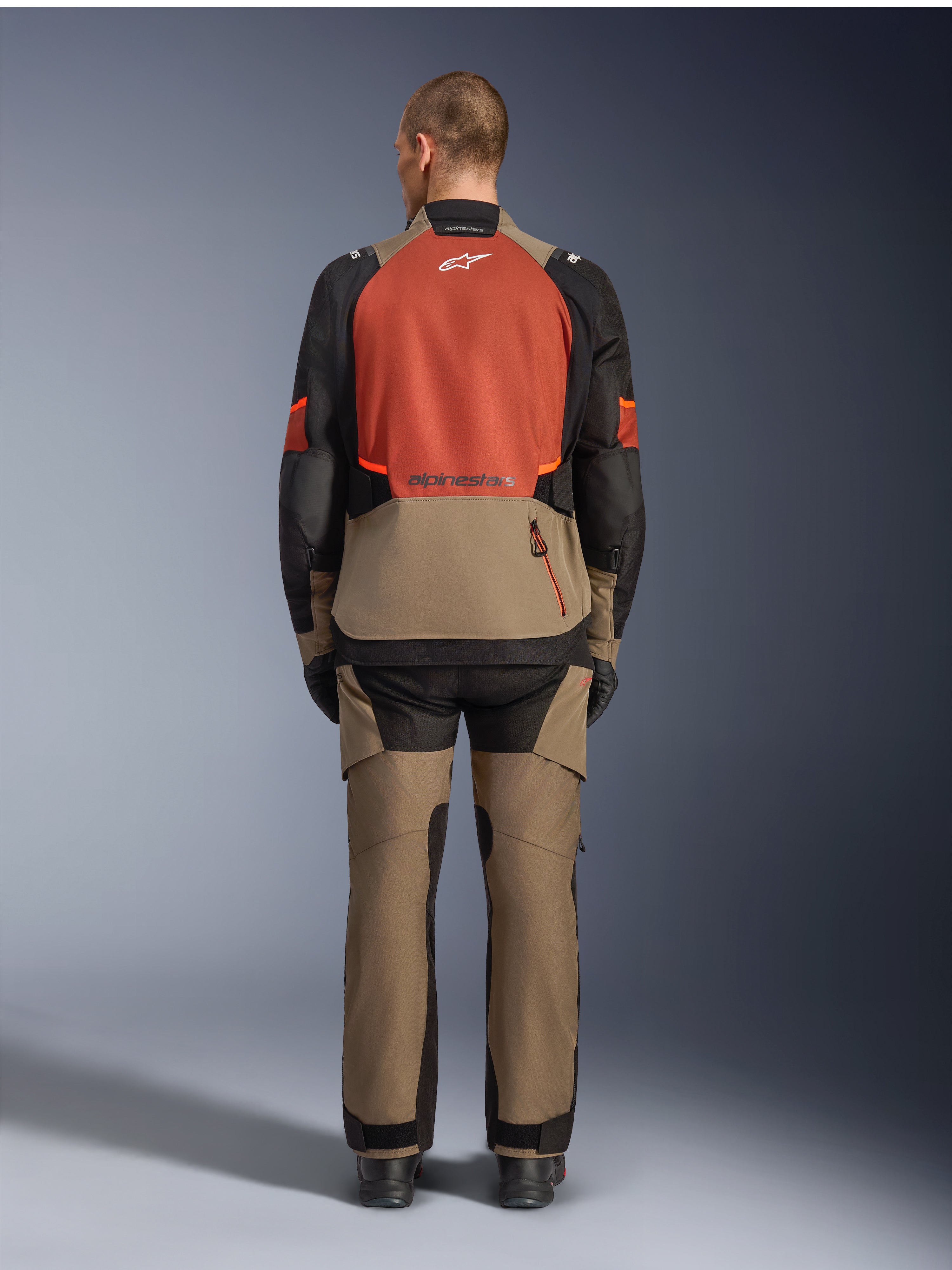 Alpinestars Andes V4 Drystar® Jacket, Walnut Rust Black, vista traseira de casaco de motociclismo touring com painel superior das costas em cor de ferrugem e secção inferior em nogueira, usado com calças de aventura a condizer e botas pretas