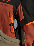 Casaco Alpinestars Andes V4 Drystar®, Walnut Rust Black, grande plano da abertura de ventilação direta com forro em malha, material têxtil durável com detalhes em laranja, botão de pressão e detalhe do logótipo Alpinestars.