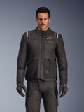 Modelo masculino a usar o Casaco Alpinestars Andes V4 Drystar® em preto, casaco de motociclismo de aventura e turismo, combinado com calças e luvas de condução pretas a condizer, com fechos impermeáveis e logótipo Alpinestars branco no peito e nos ombros, fotografia de estúdio para equipamento de condução em todas as condições meteorológicas.