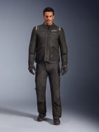 Modelo masculino a usar o Casaco Alpinestars Andes V4 Drystar® em preto, combinado com calças de motociclismo de aventura a condizer, luvas pretas e botas pretas, fotografia de estúdio de corpo inteiro exibindo equipamento técnico de touring para todas as condições climatéricas com a marca Alpinestars.